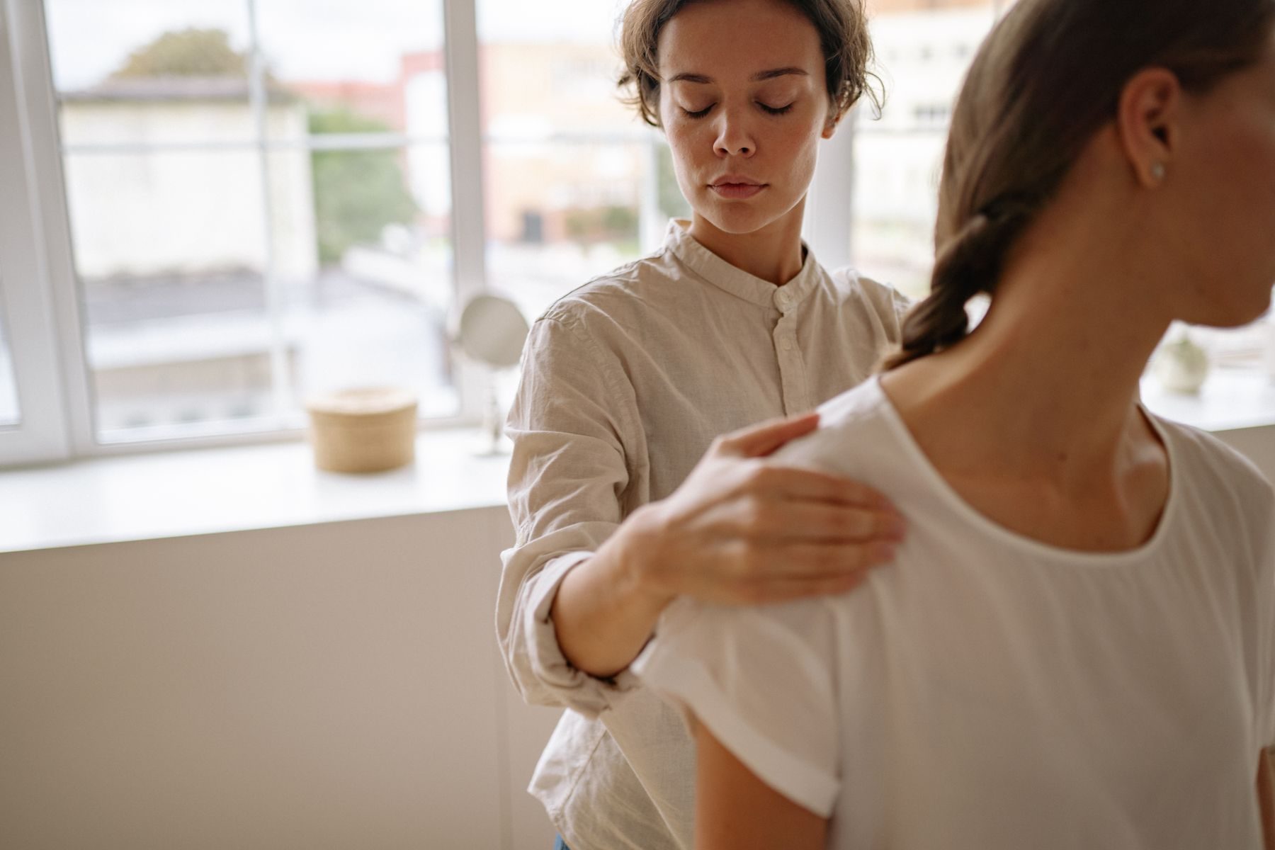 Physiotherapeutin behandelt eine Patientin in einem hellen Behandlungsraum
